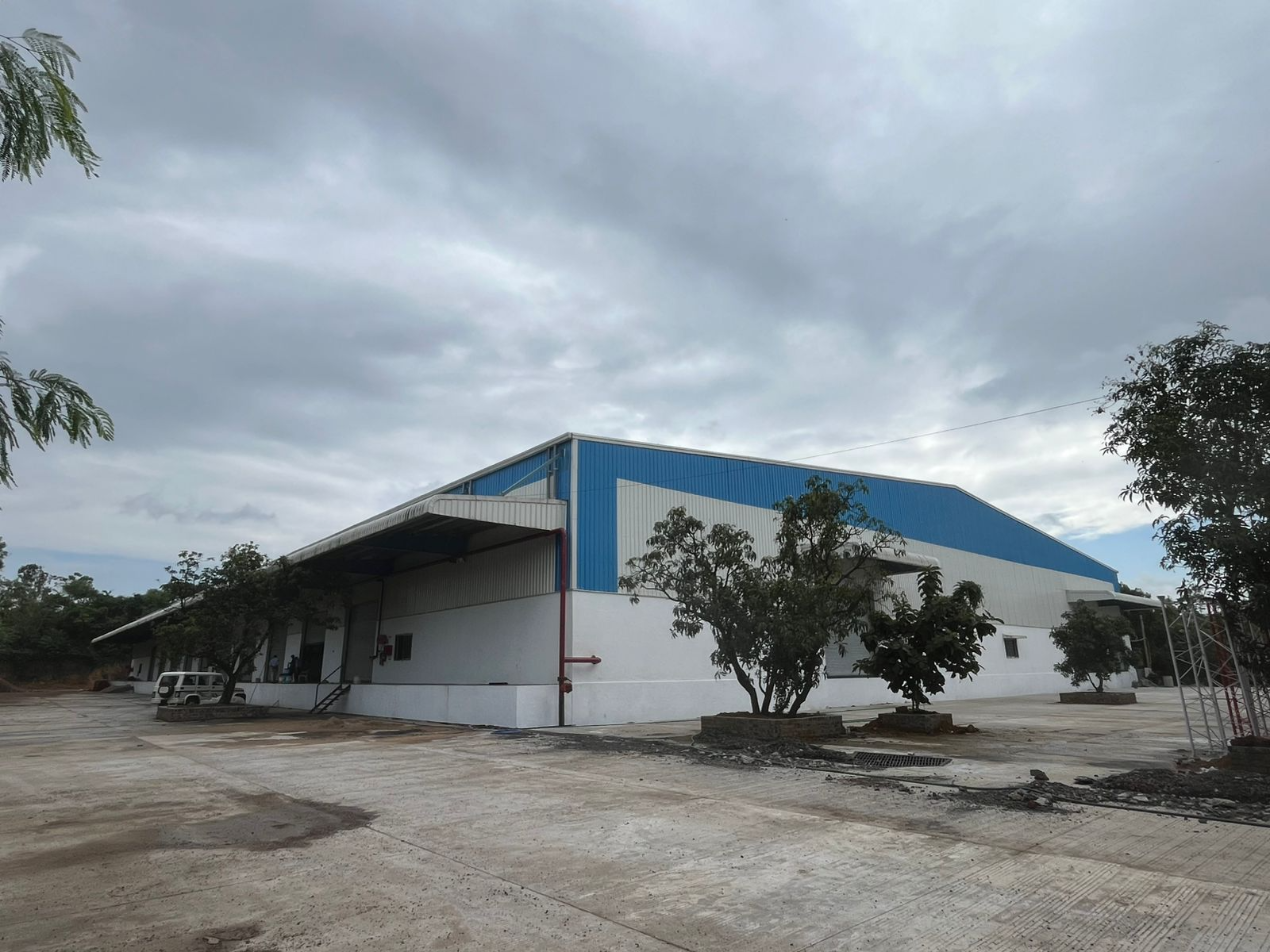 detailed peb design - Completed exterior of blue and white industrial warehouse with loading dock ramp and canopy in Gujarat - Designed at ShreeSES