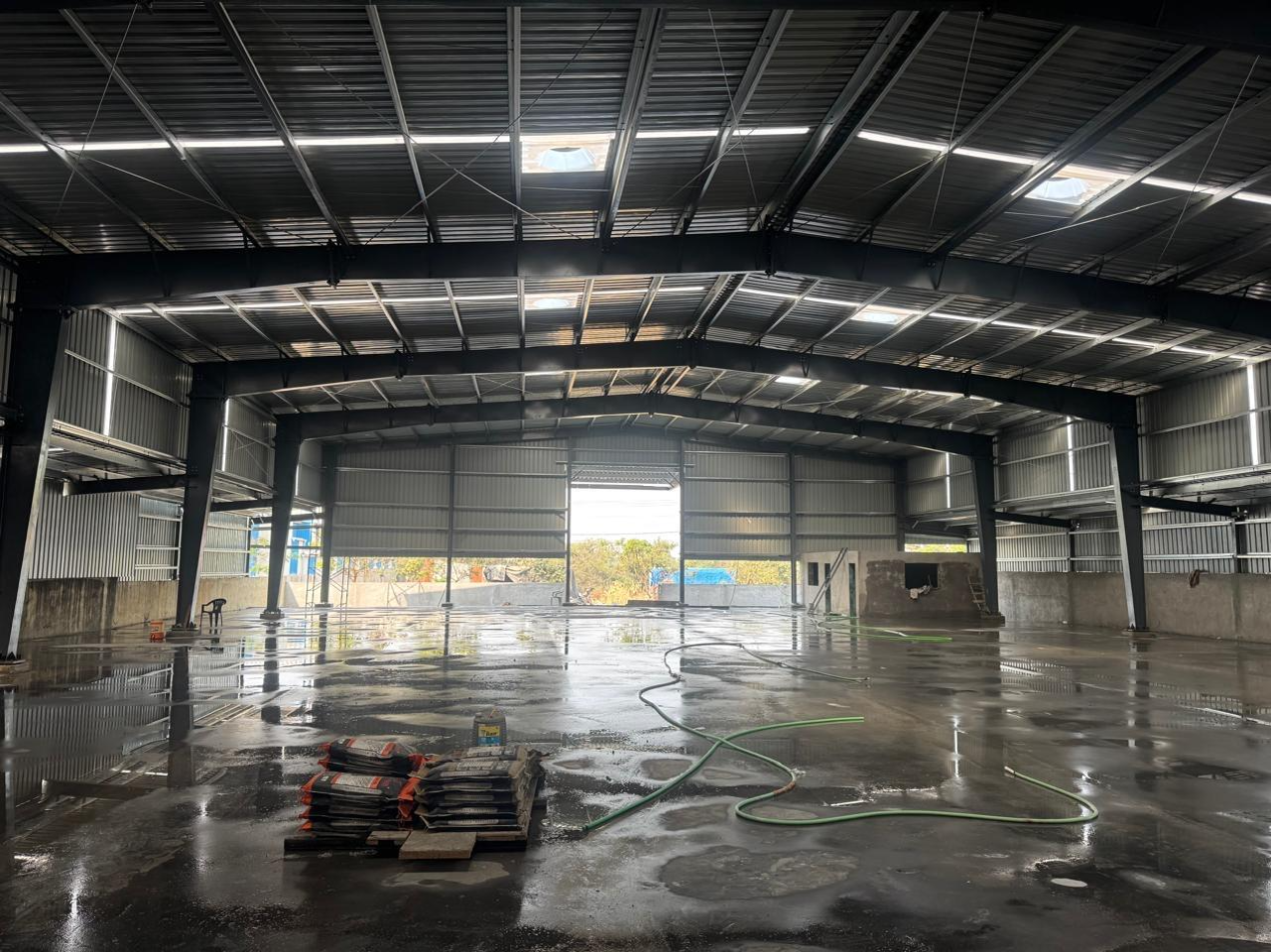 detailed peb design - Interior view of vacant industrial shed showing polished concrete flooring and steel roof trusses - Designed at ShreeSES